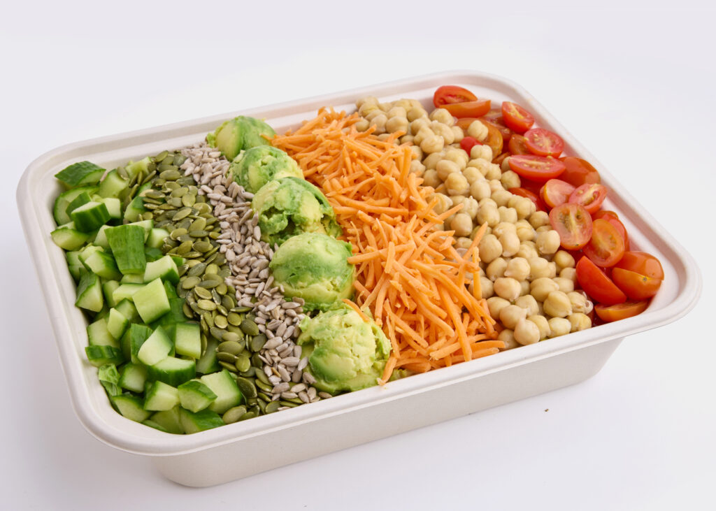 A colorful salad with avocado, cucumbers, chickpeas, cherry tomatoes, and cashew dressing.