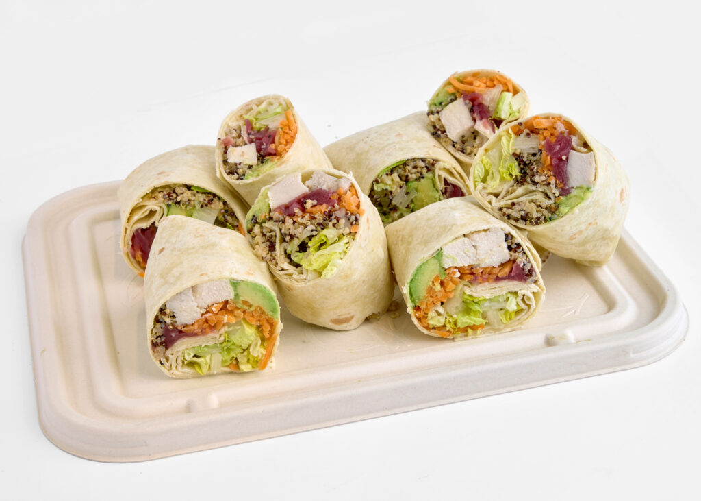 A platter of halved wraps filled with grilled chicken, avocado, and a zesty chipotle sauce.