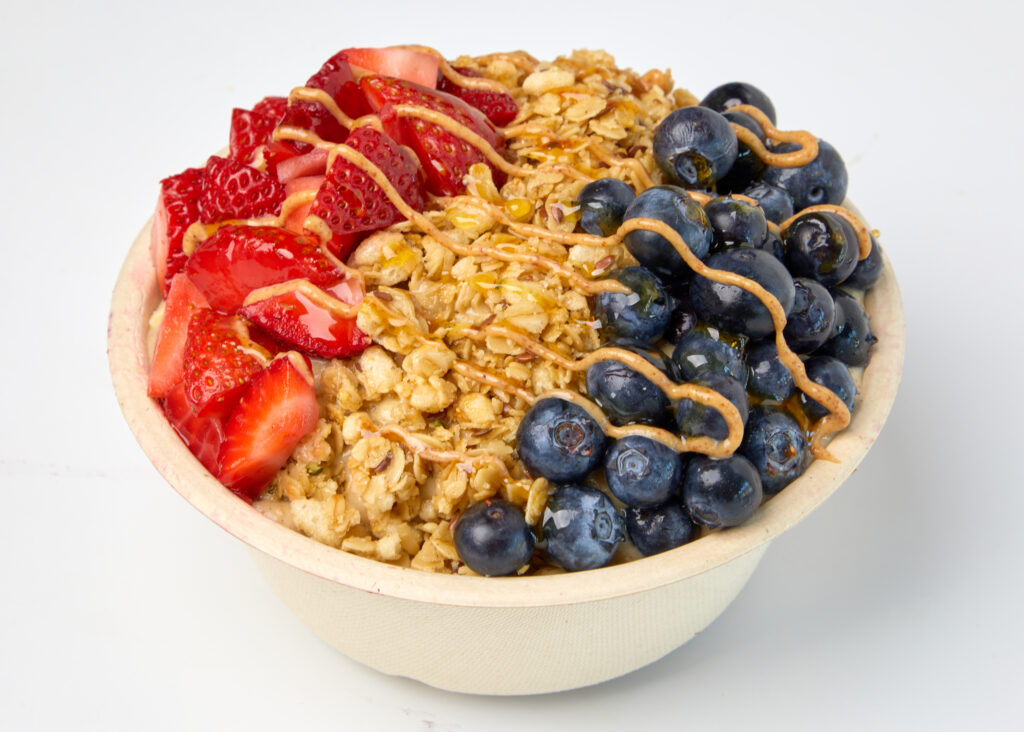 A snoothie bowl with banana, oats, almond butter, and protein, topped with berries and granola.