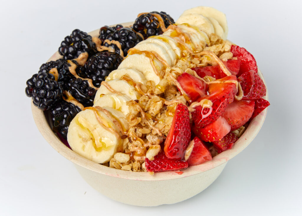 A pitaya-based bowl topped with strawberries, blackberries, bananas, granola, and almond butter.