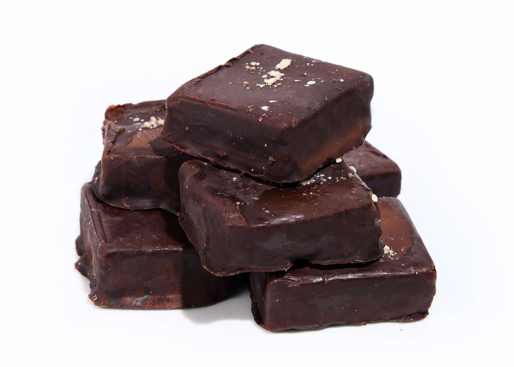 A glossy, dark chocolate bonbon with a rich nutty interior.