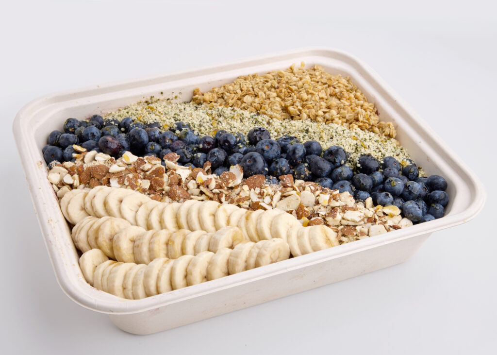 A nutritious catering tray with banana slices, blueberries, granola, almonds, and hemp seeds.